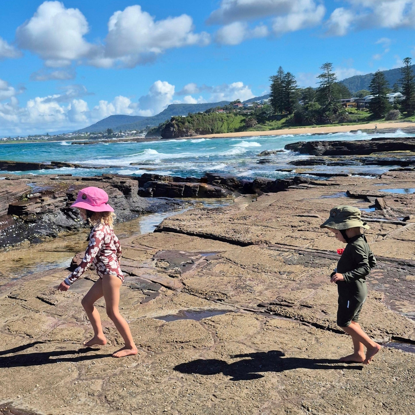 Kids walking on reef waring surf hats pink and green