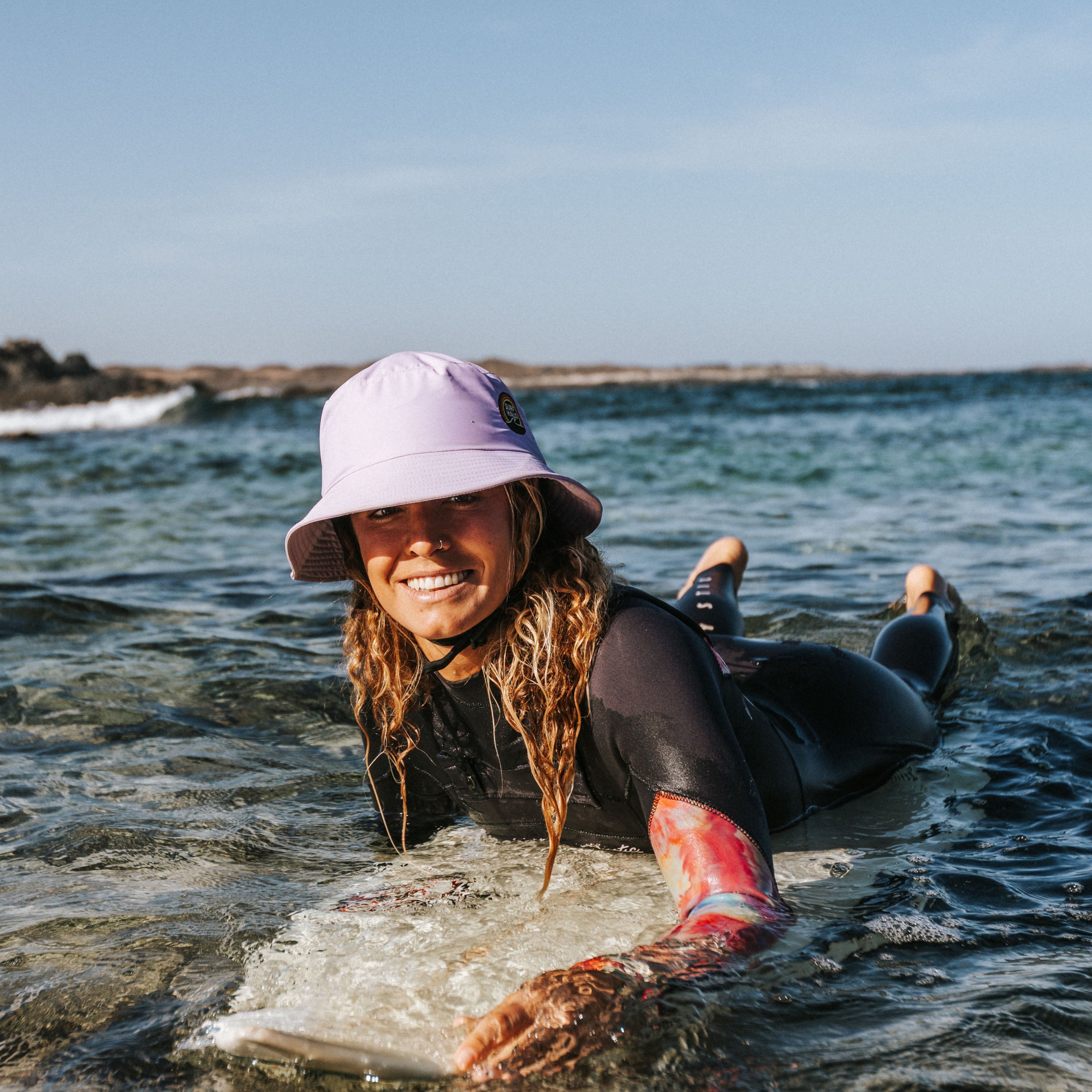 women wearing bucket surf hat helmet in the water over a surfboard
